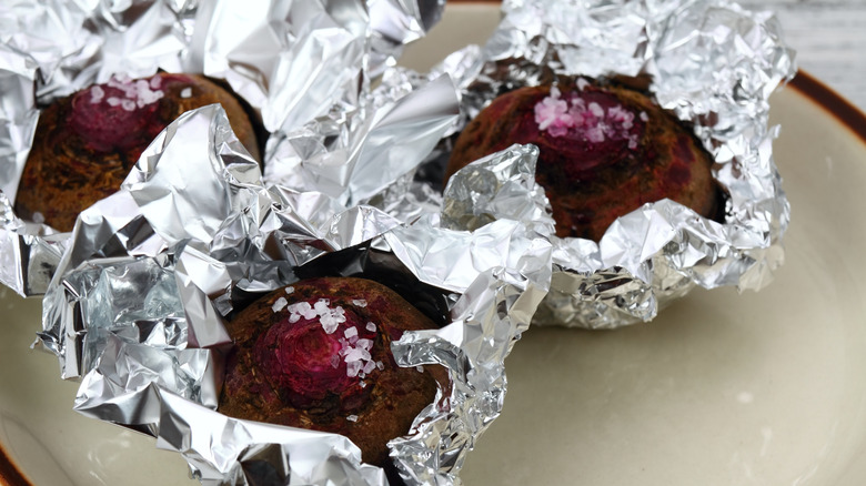 Roasted beets in aluminum foil with salt on top of counter.