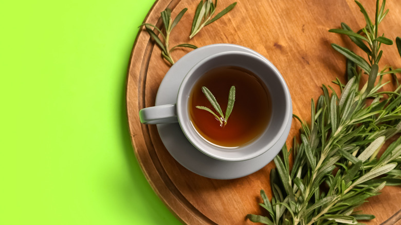 a cup of hot rosemary tea with fresh rosemary on the side