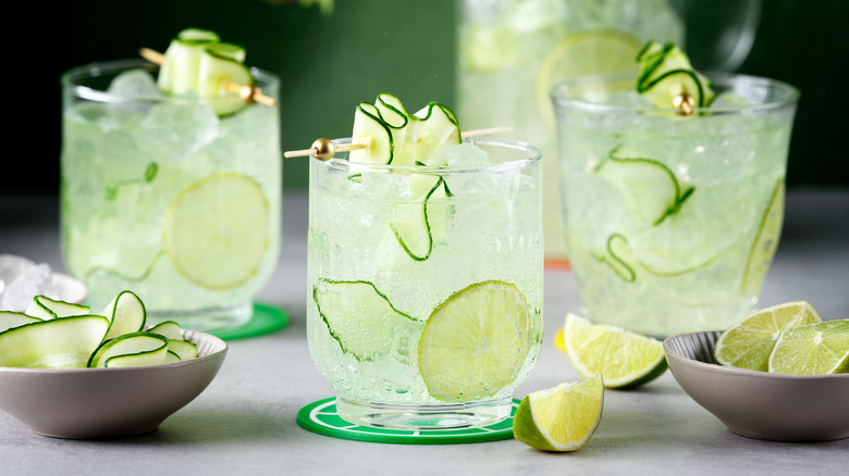 Three mixed drinks with a cucumber garnish