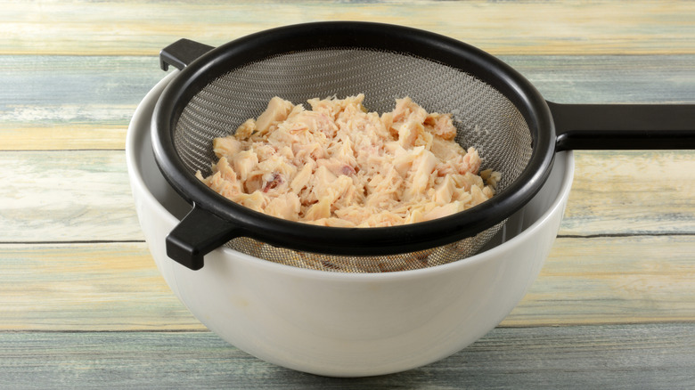 Tuna in colander placed over white bowl