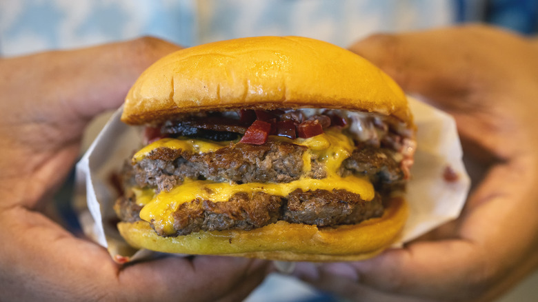 Closeup of hands holding a cheeseburger