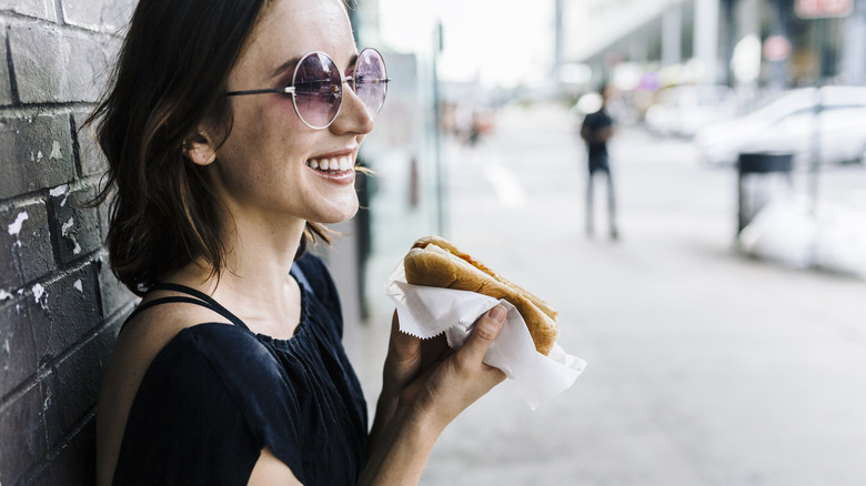 Person enjoying a hot dog on the go