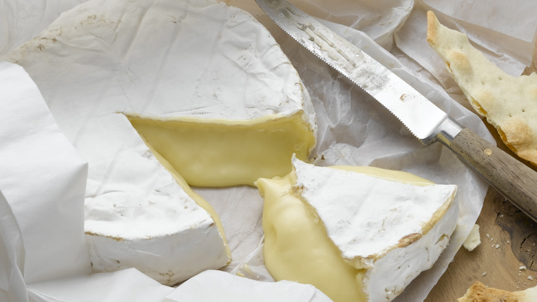 Soft, melted Brie cheese cut into a wedge shape with a knife