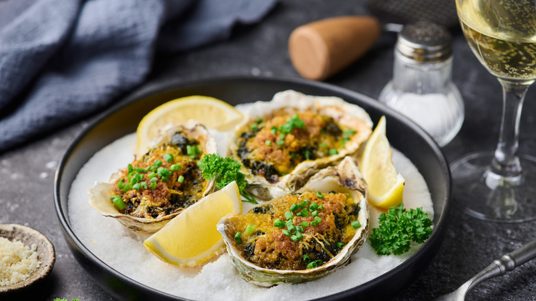 oysters Rockefeller with slice of lemon served on plate with ice