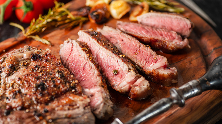 A sliced cooked steak on a cutting board.