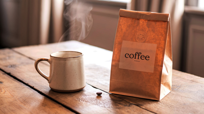 A cup of coffee next to a coffee bag with a valve.