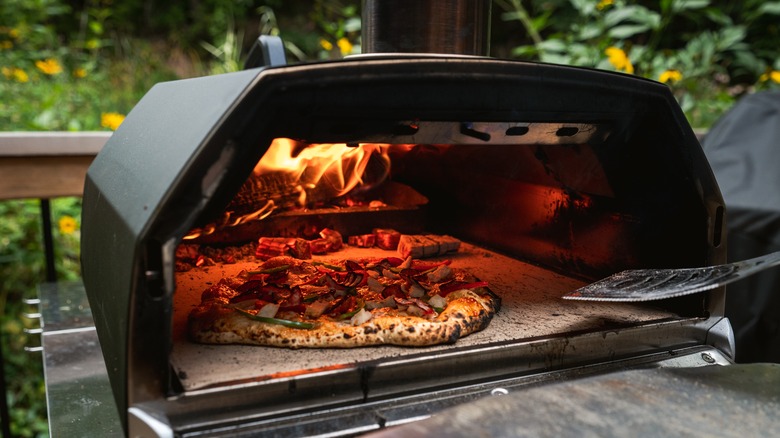 Pizza in a portable wood-fired pizza oven outside