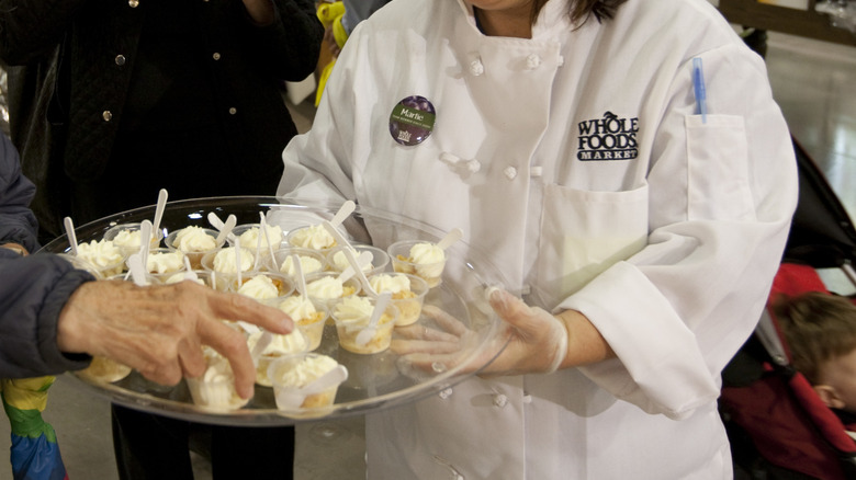 Woman passing out a tray of free sample desserts at Whole Foods