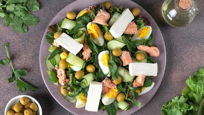 Green salad with feta cheese, sliced hard-boiled eggs, green olives, and canned salmon