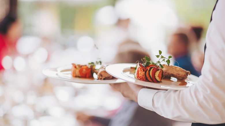 A server bringing plates to a table.