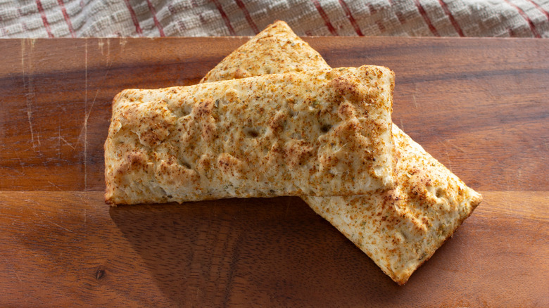 two cooked Hot Pockets crossed over each other on a wooden table