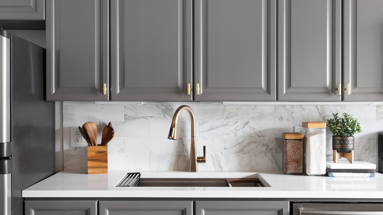 A minimalist kitchen with gray cabinets and marble splashback