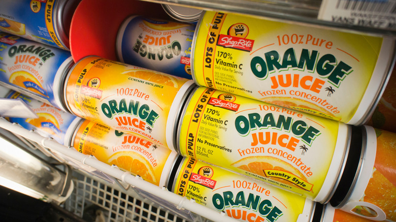 Cans of frozen orange juice concentrate in a grocery store freezer.