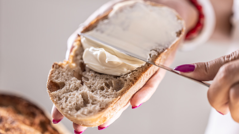Hand spreading butter on toast
