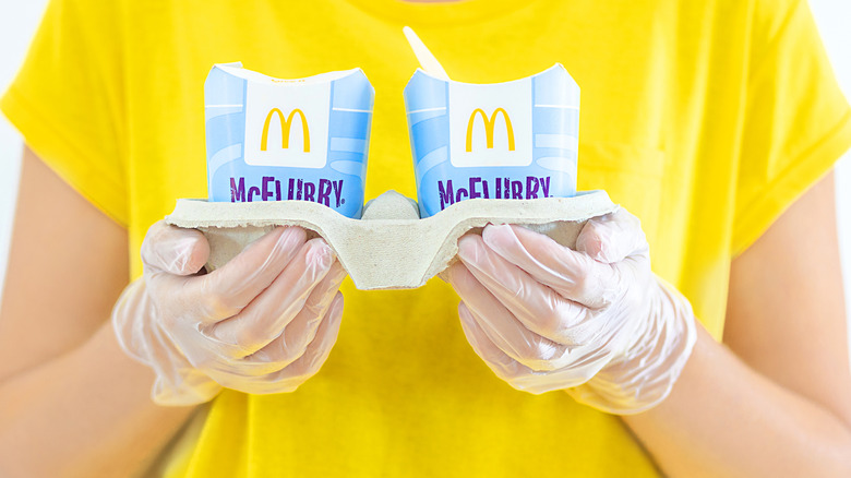 Hands in vinyl gloves presenting McFlurry desserts.