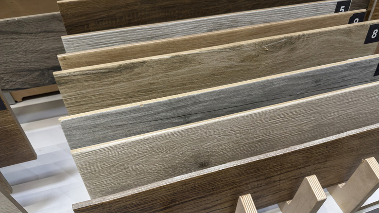 Solid planks of wood-finish laminates stacked on a display shelf in a hardware store.