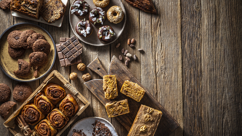 A flat lay of an array of different desserts arranged casually and set on a wooden background