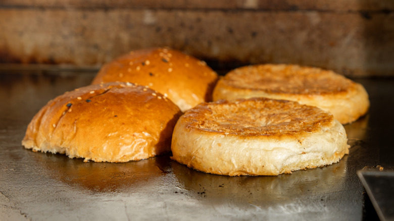 Cheeseburger buns upside down on grill top.