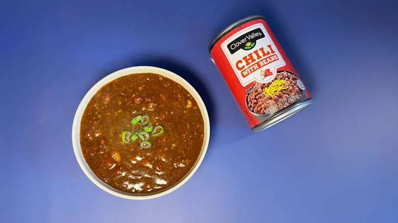 Can and bowl of Clover Valley chili with beans displayed on a blue counter