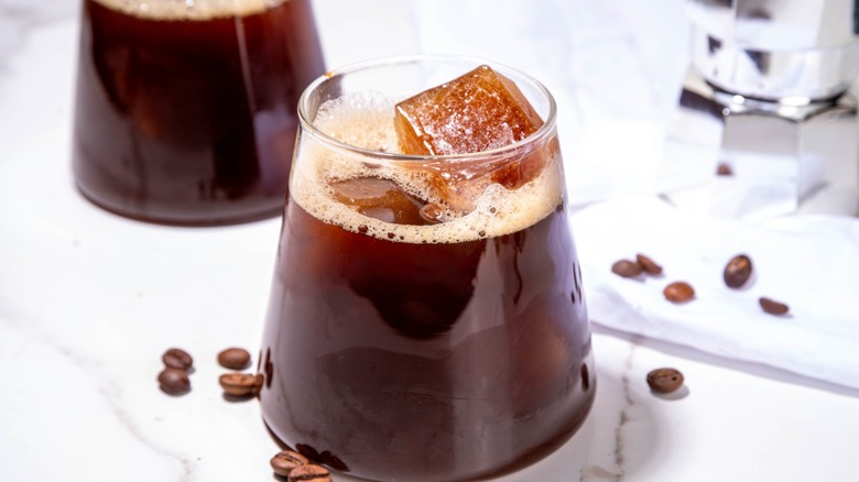 Coffee cocktails over ice in a glass surrounded by coffee beans