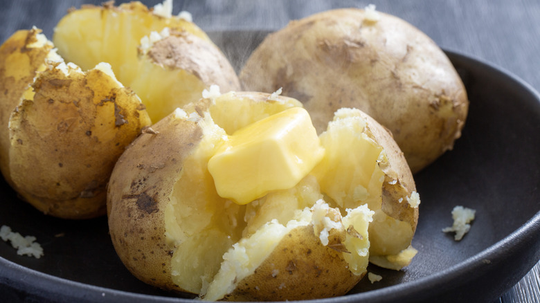 plate of baked potatoes with slab of butter