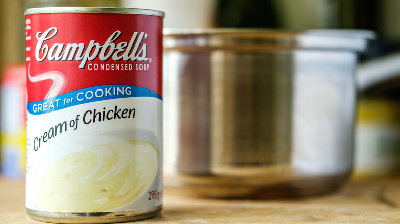 A can of Campbell's Cream of Chicken soup with a blurry metal soup pot in the background