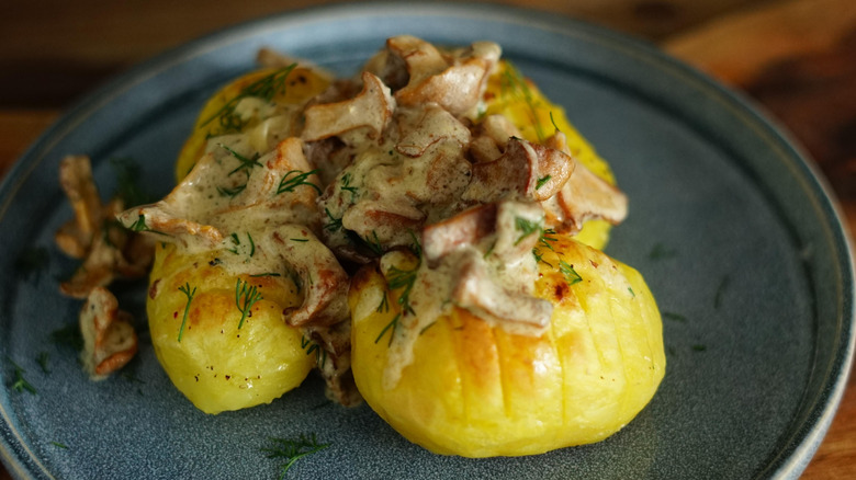 Baked potatoes topped with mushrooms, creamy sauce, and fresh herbs