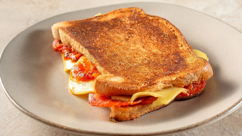 Pizza sandwich with white cheese, pasta sauce, and pepperoni on toasted white bread