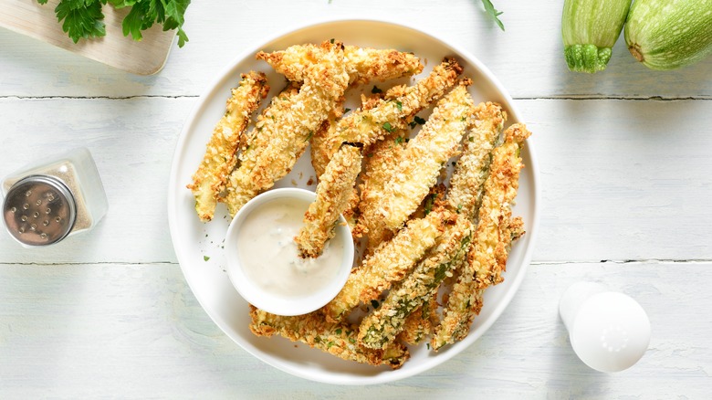 Crispy zucchini fries in a plate with a dip