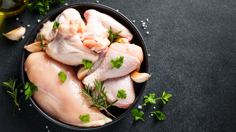 uncooked chicken in pan with herbs