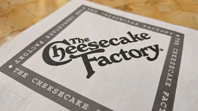 A cheesecake factory napkin on a wooden table.