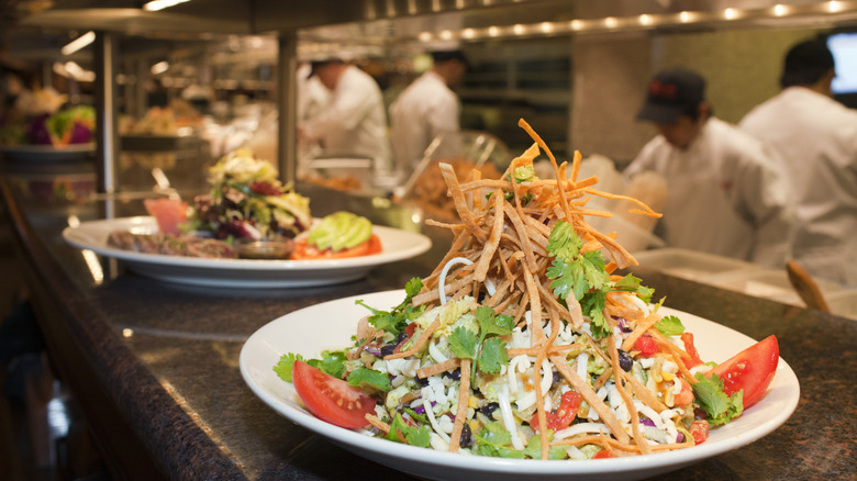 A plated salad waiting on the kitchen pass in a restaurant.