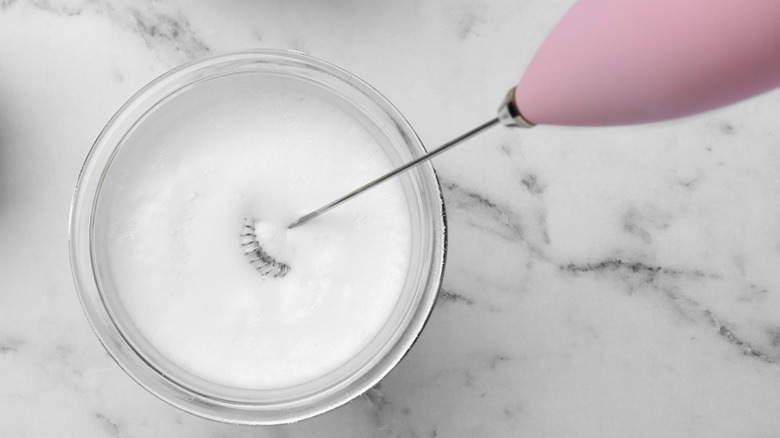 an electric milk frother aerates a vanilla protein shake