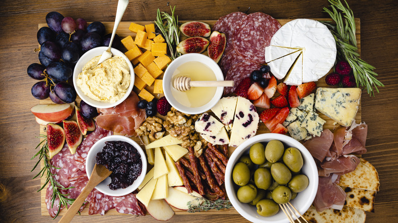 A bountiful cheese and charcuterie board photographed from above.