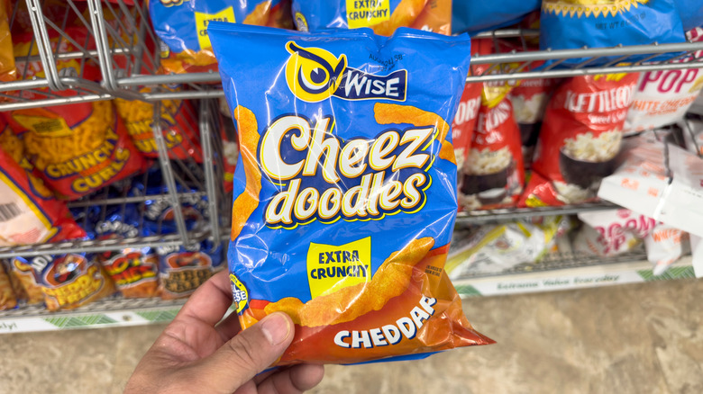 Hand holding a bag of Cheez Doodles in a grocery store