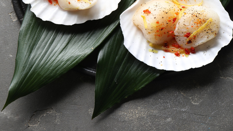 Raw scallops with seasoning on half shells
