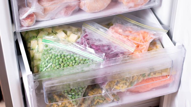 Frozen bags of vegetables in freezer drawer.