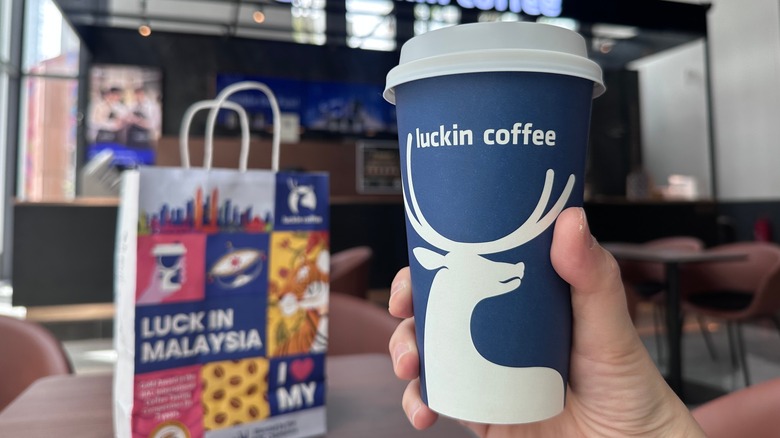 hand holding a Luckin Coffee branded to-go coffee cup