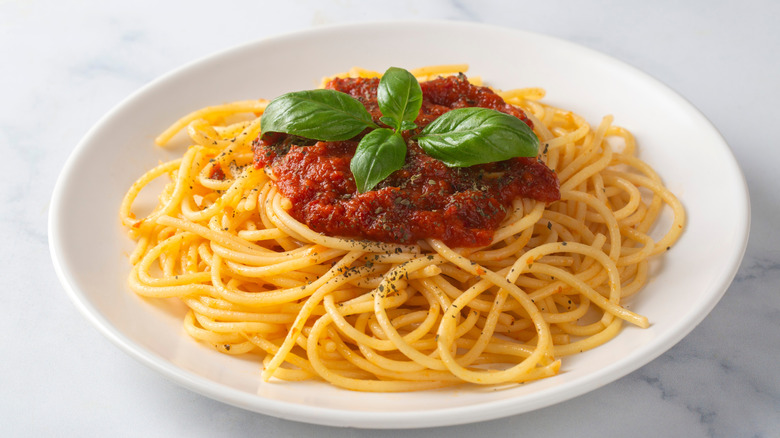 Plate of spaghetti with tomato sauce and fresh basil leaves on top