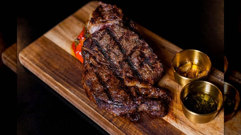 A grilled ribeye steak on a wooden board