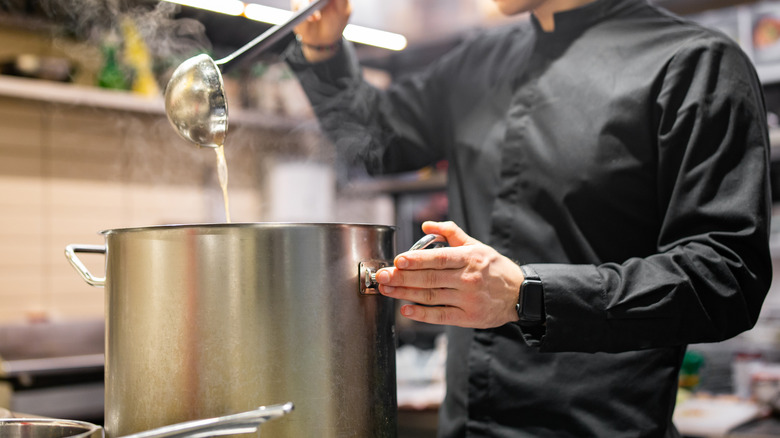 Chef pouring soup in restaurant kitchen