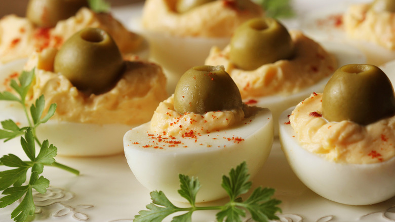 deviled eggs topped with green olives