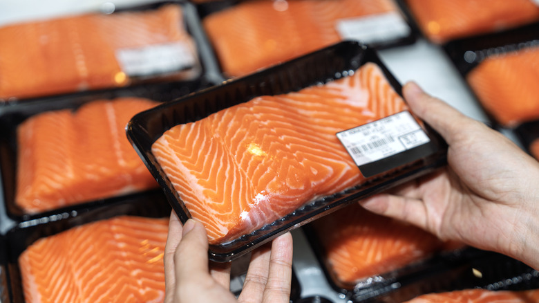 Woman selecting packaged, fresh salmon filets at a grocery store