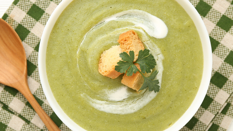 A bowl of broccoli soup garnished with croutons and parsley