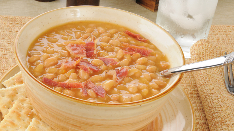A bowl of bean soup topped with bacon.
