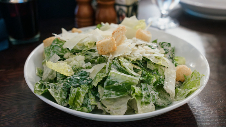 Caesar salad in a white bowl on a wooden table