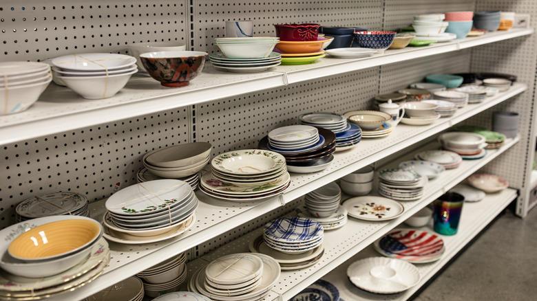 Assorted dishware lines shelves at a thrift store.