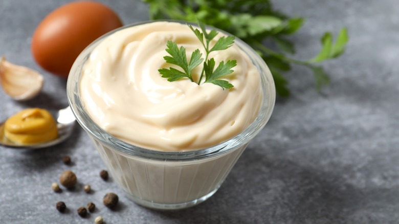 A bowl of mayonnaise garnished with an herb.
