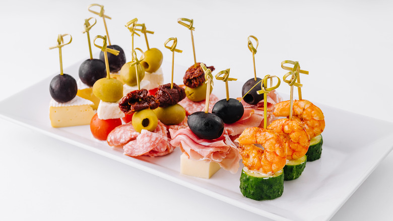 A variety of finger food on a white plate, set against a white background.