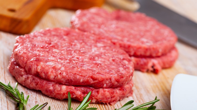 Raw burger patties on cutting board